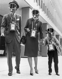 picture of a 1950s era family with dad, mom and son all dressed in their sunday best including gas mask